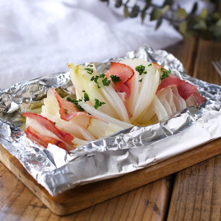 木の皿に盛り付けられた玉ねぎとチーズのホイル焼き