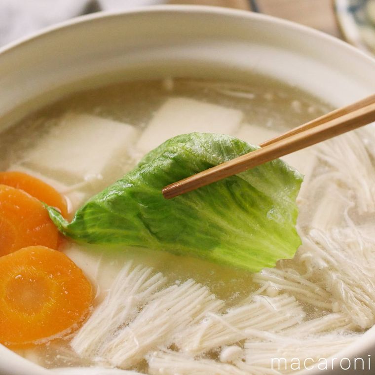 白い鍋に入ったレタスと豆腐のヘルシーしゃぶしゃぶのレタスを箸でつかんでいる様子