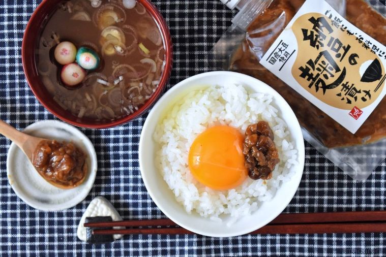 納豆の麹漬けと卵黄をのせたごはん、パッケージ、みそ汁、箸、納豆の麹漬けをのせた小皿