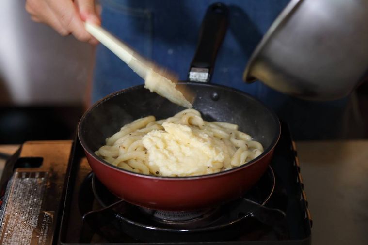 焦がしバターソースを和えたパスタにチーズソースを加えた様子