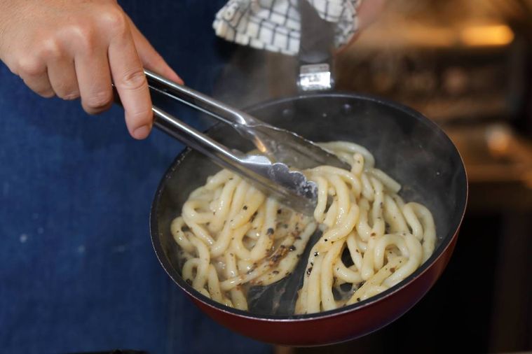 焦がしバターソースとパスタをパスタを和えている様子