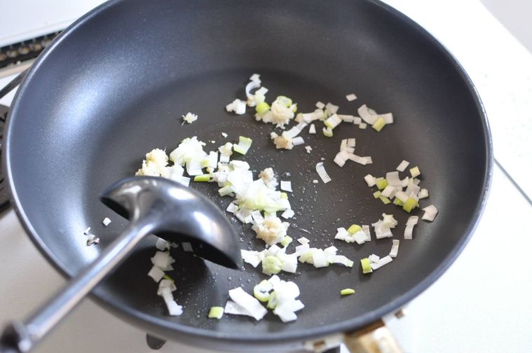 サラダ油を熱したフライパンで長ねぎ、にんにく（みじん）、しょうが（みじん）を炒める様子