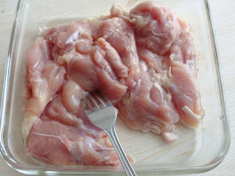 鶏もも肉にフォークを刺して穴を開けている様子