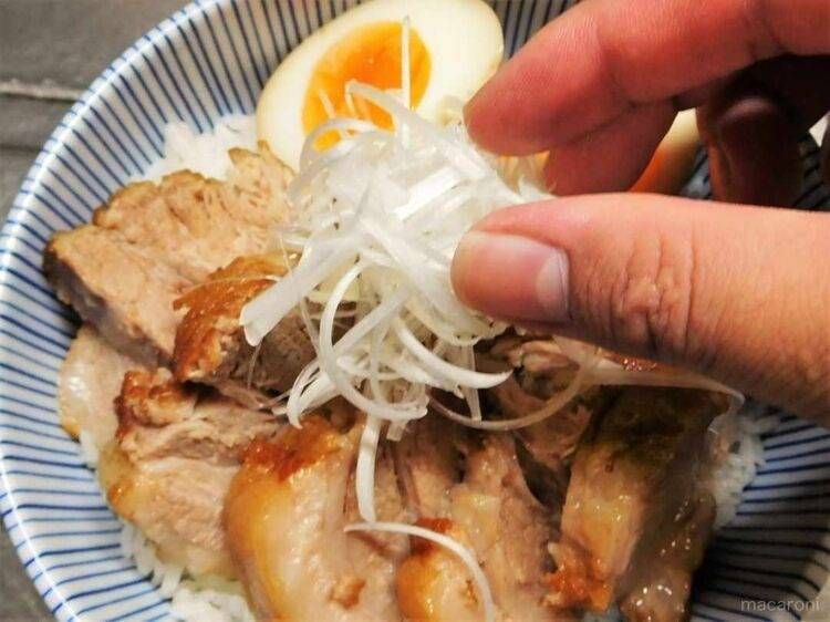 チャーシュー丼にネギをトッピングしている様子