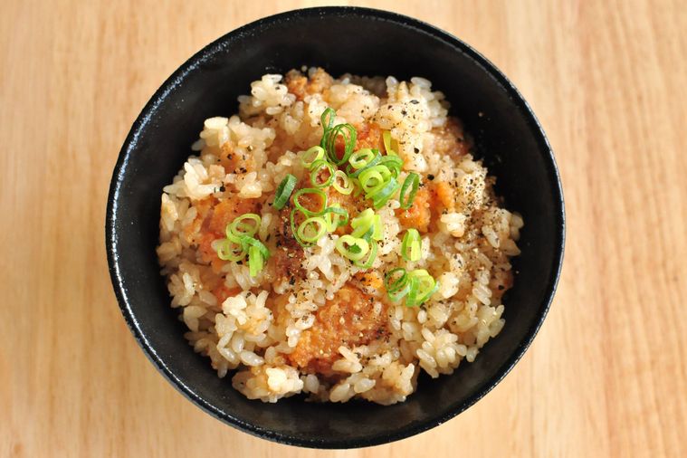 黒いご飯茶碗にファミチキご飯を盛り付けて小ねぎと粗挽き黒こしょうを散らした様子