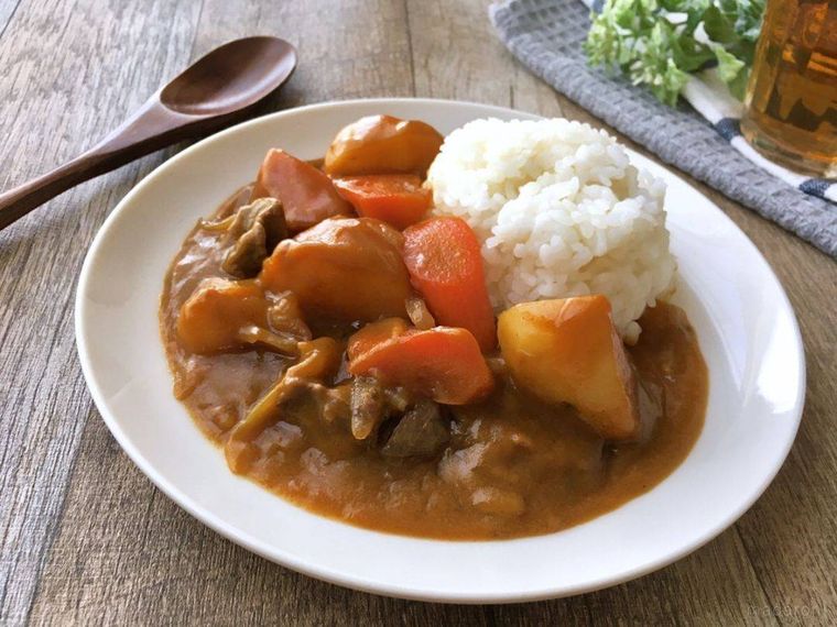 白い丸皿に盛り付けられた肉じゃがカレーの斜俯瞰のより画像