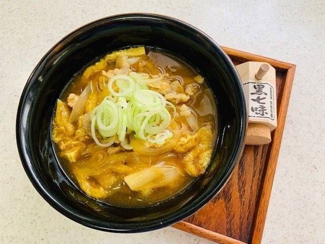 長ネギをトッピングした豚肉と玉ねぎ、油揚げのカレーうどんの黒い丼ぶり