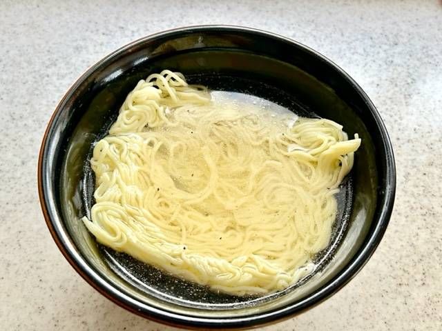 黒い丼に入った焼きそば麺とスープ