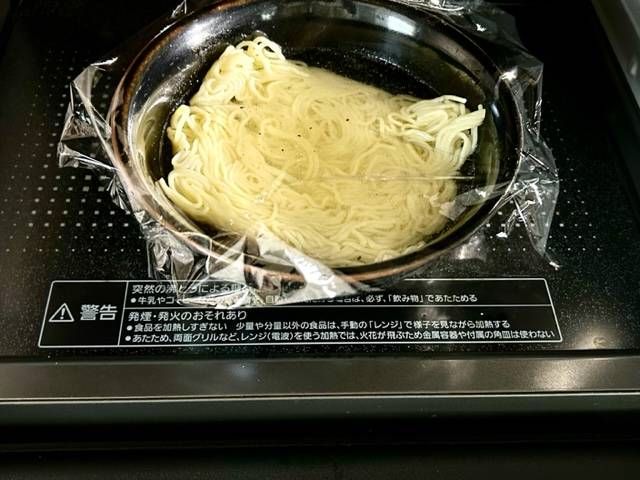 ラップをかけたラーメン丼を電子レンジに入れる様子