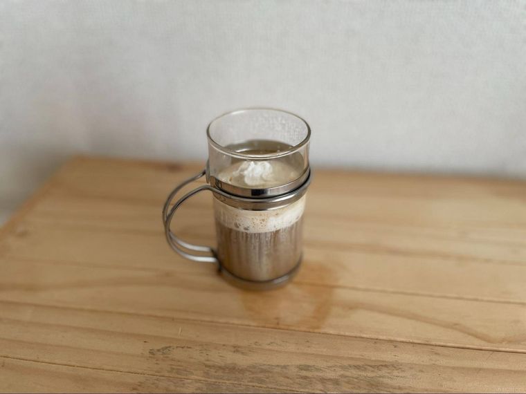 木製の机の上に置かれた生クリームがトッピングされたコーヒー