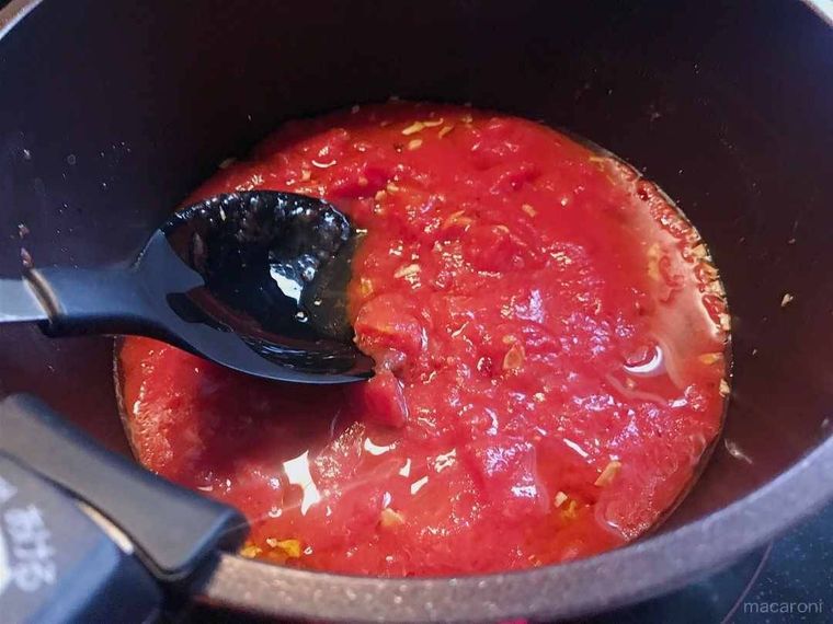 鍋に入ったトマト缶を炒めている様子