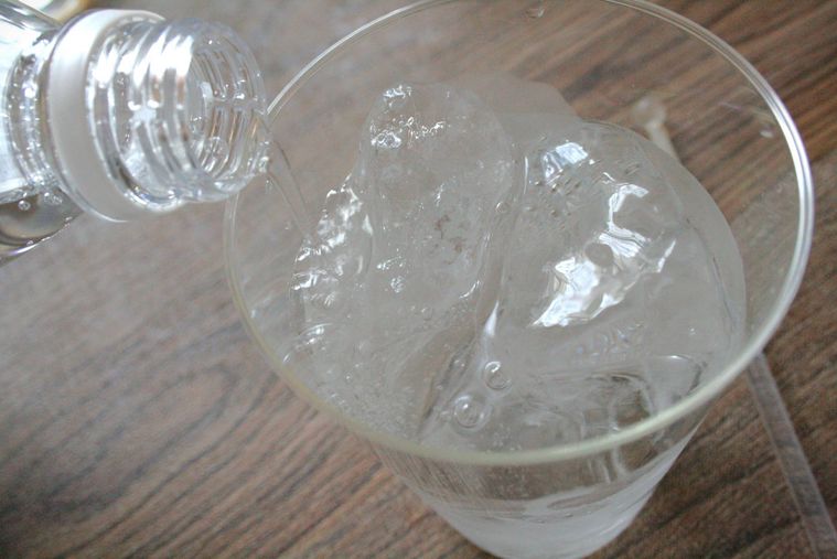 氷と焼酎の入ったグラスに強炭酸水を注いでいる様子