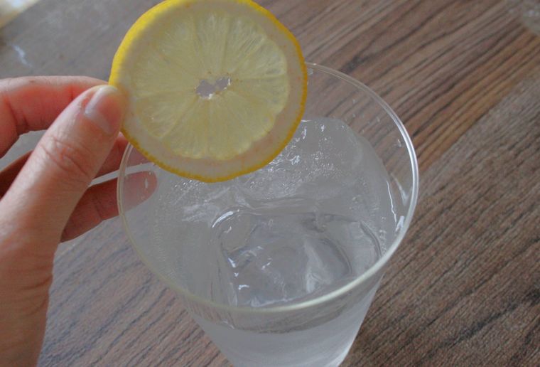レモンサワーに輪切りレモンをトッピングしている様子