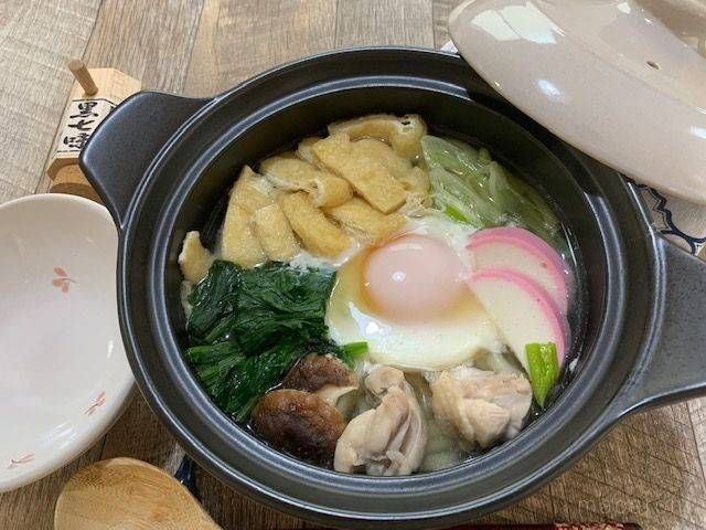 鶏肉や卵、しいたけ、ほうれん草などの具材が入った鍋焼きうどん