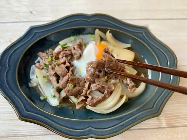 青い皿に入れて卵を落とした牛肉と玉ねぎのすき焼き風煮