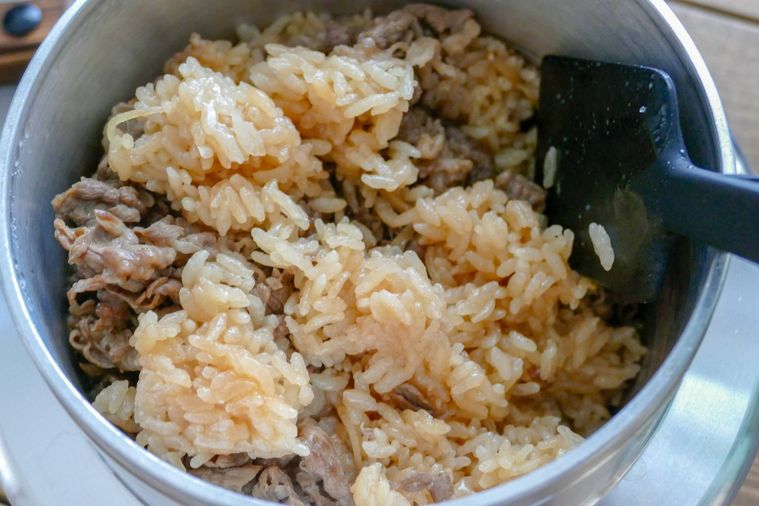 炊きあがった牛肉の炊き込みご飯を混ぜる様子