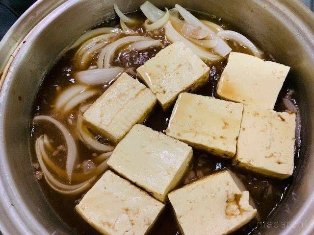 煮汁で煮込んでいる豆腐と玉ねぎが入った鍋