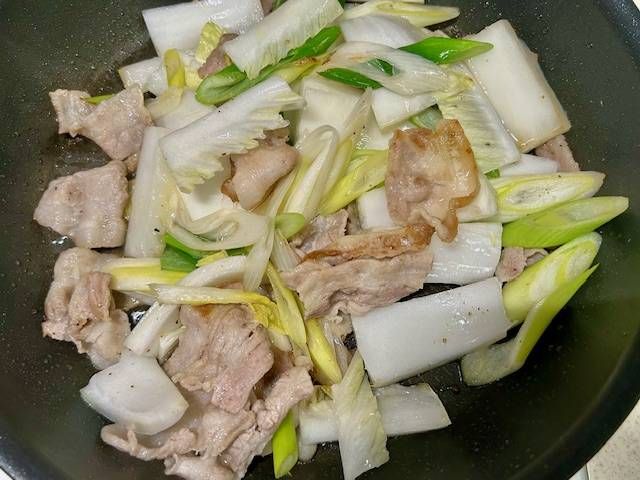 豚バラ肉と白菜、長ねぎを炒めている様子