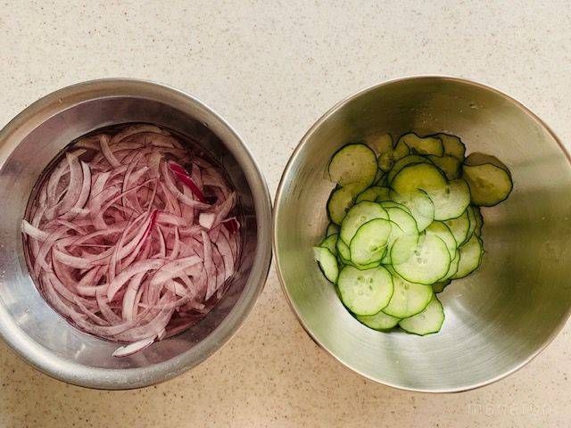 水にさらした紫玉ねぎとスライスしたきゅうりが入った金属ボウル