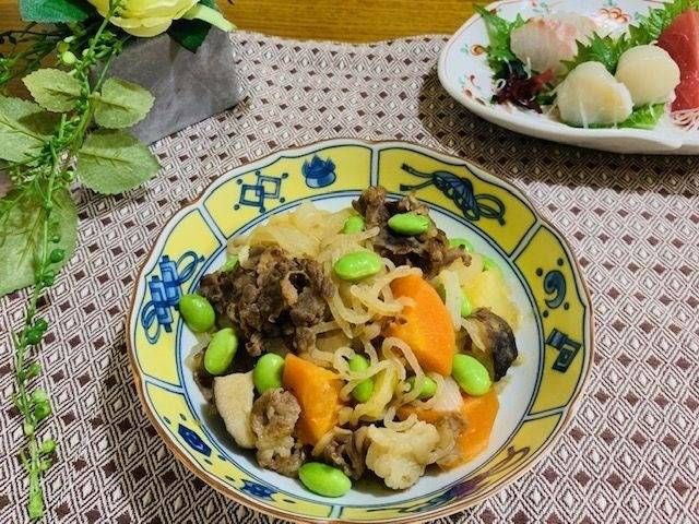 黄色に器に盛られた肉じゃがが並んだ食卓