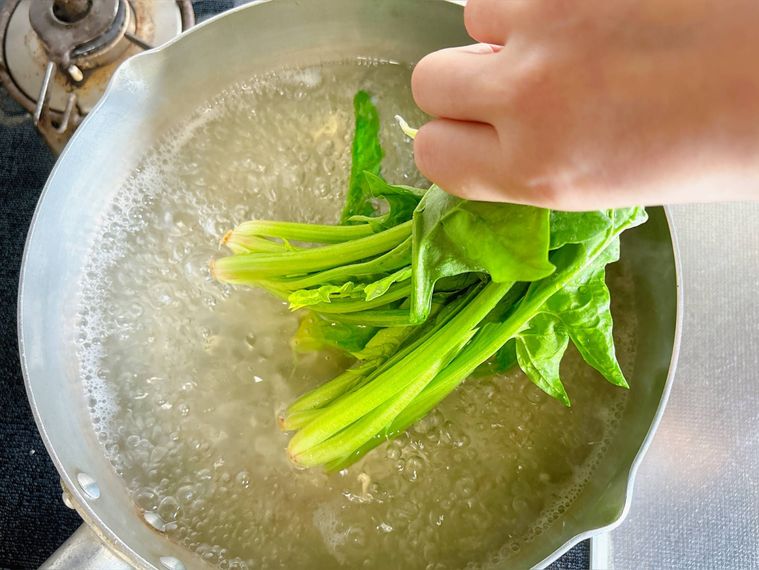 ほうれん草の根元をお湯に入れる様子