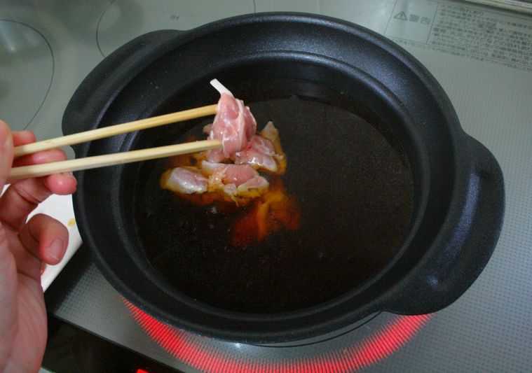 鍋に鶏もも肉を入れている様子