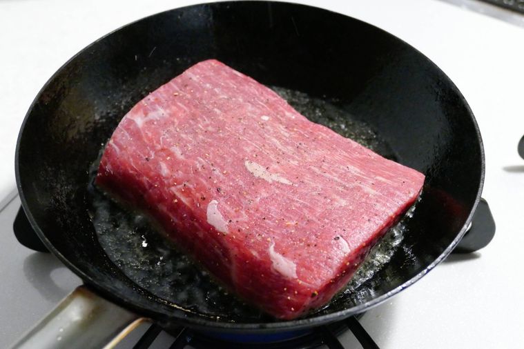 牛もも肉をフライパンに入れて焼く様子