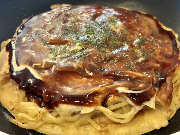 モダン焼きにソースと青のりをトッピングするところ