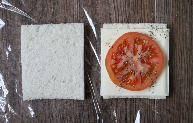 サンドイッチ用食パンにスライスチーズとトマトをのせている様子