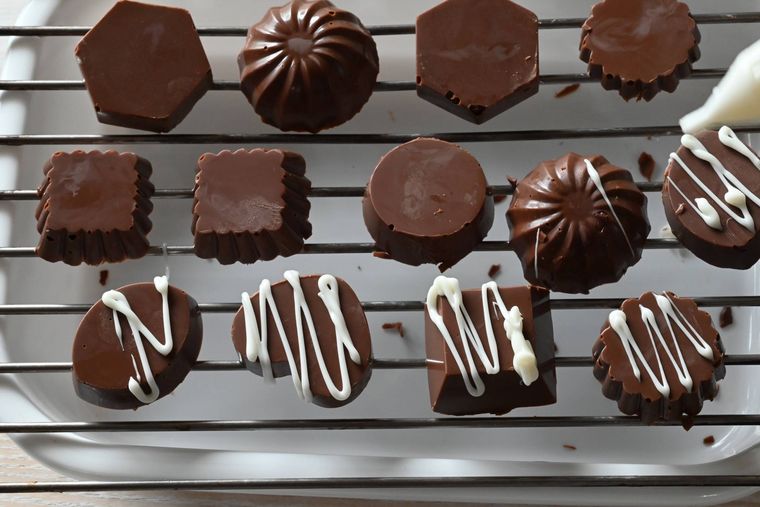 網の上に置かれているチョコレートにチョコペンでデコレーションしている様子