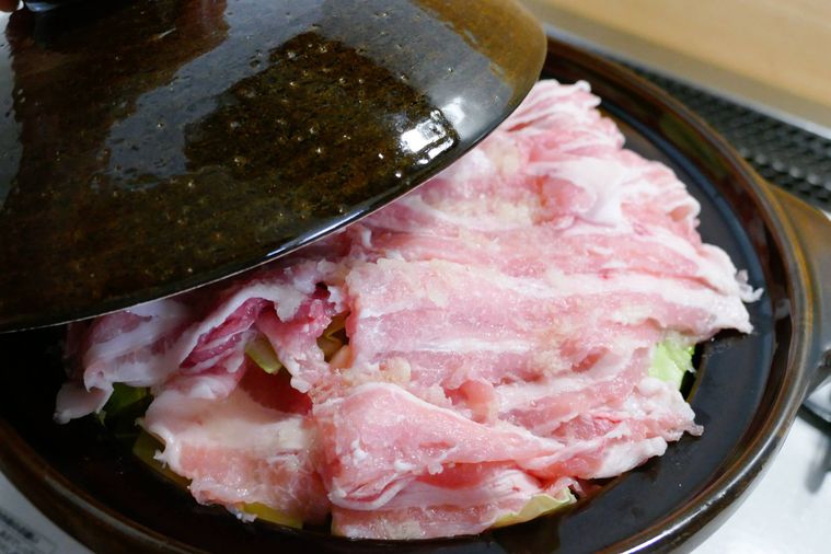 キャベツと豚バラ肉が入っている鍋に蓋をする様子