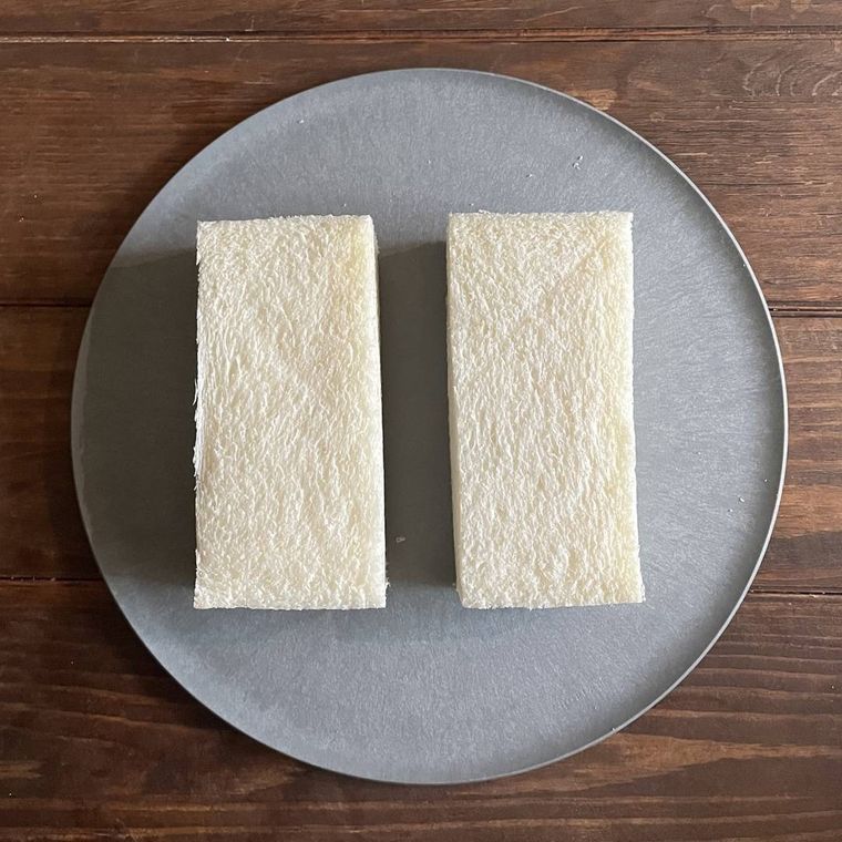 グレーの皿に乗った、耳をカットした食パン