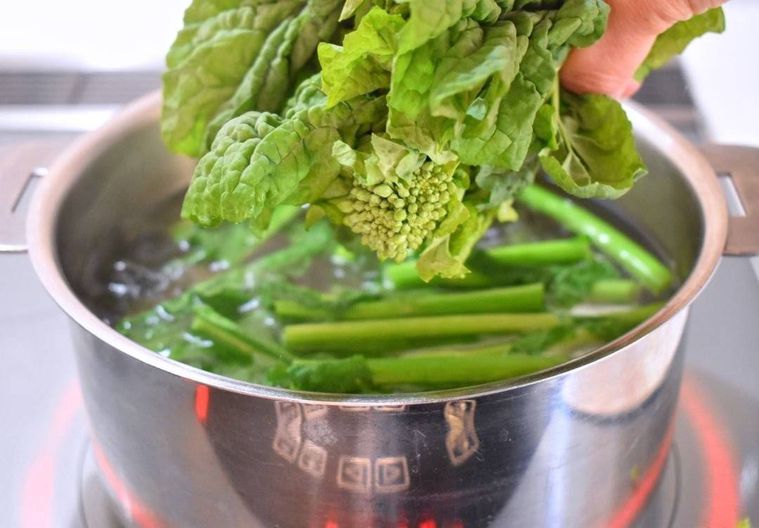 沸騰したお湯に菜の花のつぼみの部分を入れるところ