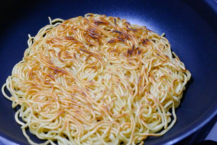 フライパンで焼きそば麺の表面に焼き色をつける様子