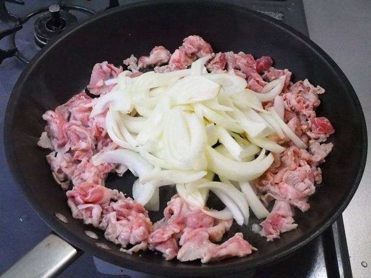 フライパンに豚肉と玉ねぎを入れて炒めている様子