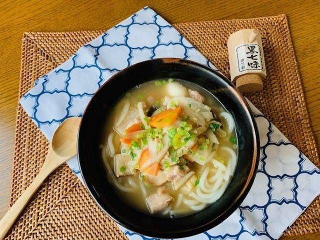 鶏肉と大根、ニンジンなどの具材がのったけんちんうどんの黒いどんぶり