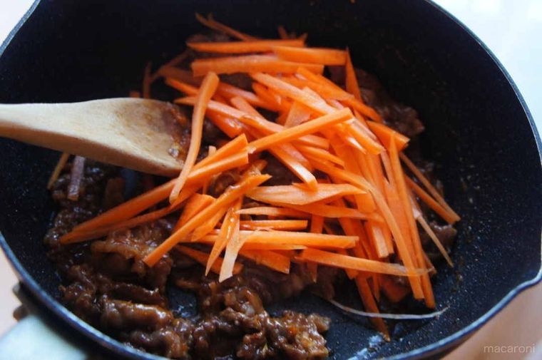 鍋で牛肉とにんじんを炒めている様子