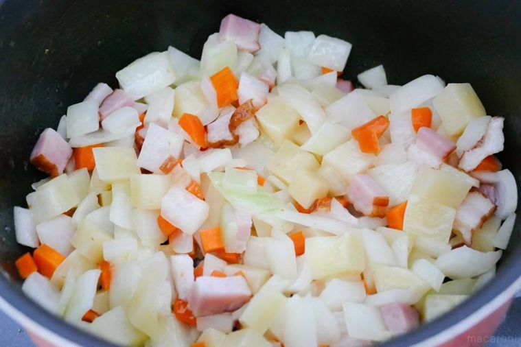 野菜とベーコンを鍋で炒める様子