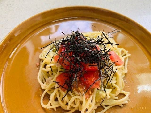 きざみのりとトマトをのせたアボカドとツナのパスタをのせた茶色い皿