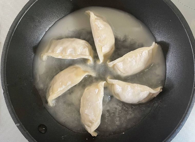 フライパンに入った餃子と水で溶いた小麦粉