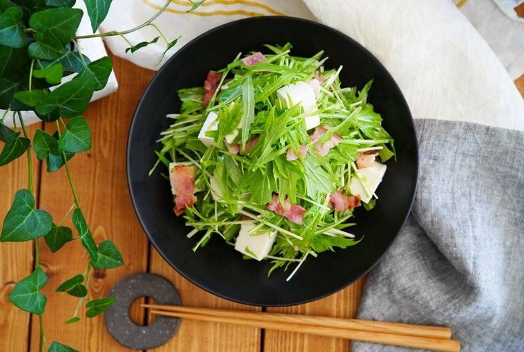 黒い丸い器に盛られた水菜と豆腐のサラダ