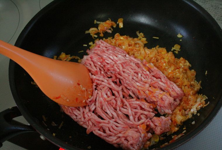 長ねぎを炒めたフライパンに豚ひき肉を入れた様子