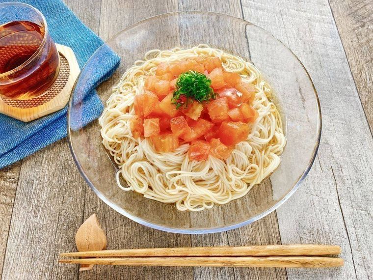 透明なガラス皿に盛られた、大葉がトッピングされているトマトそうめん