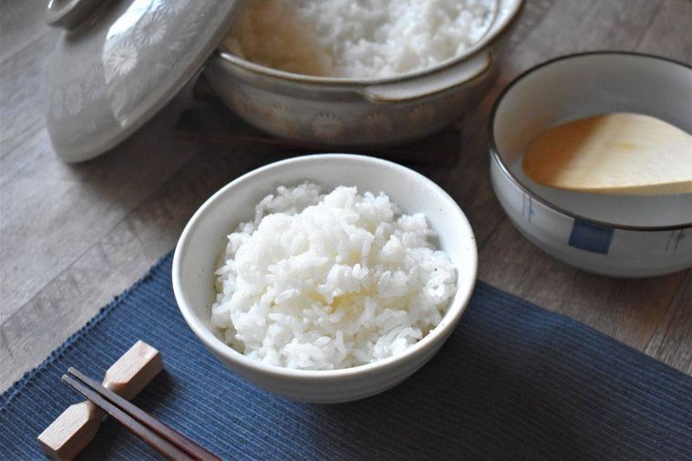 テーブルの上に土鍋炊きごはんが盛られた茶碗、お箸、ごはんが入った土鍋、しゃもじが並んでいる