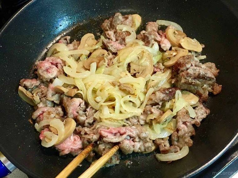 半生の牛肉や玉ねぎなどを炒めている様子