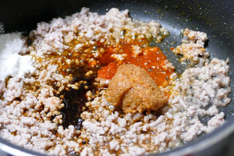 豚ひき肉が入っているフライパンに調味料を加えた様子