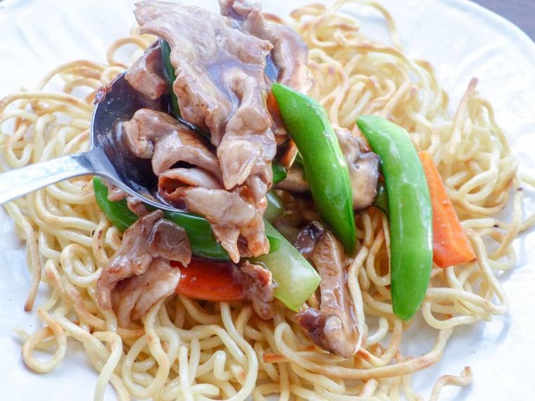 うっすら焼き色のついた中華麺にあんかけをかける様子