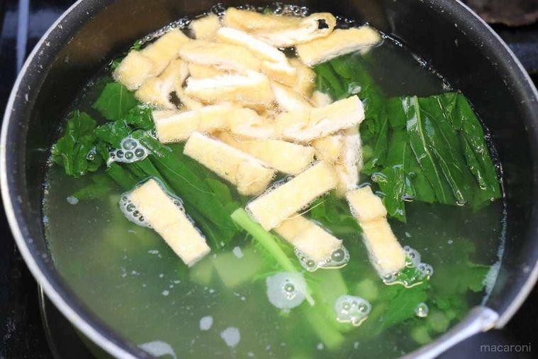 鍋に入っただし汁と大根葉と油揚げ