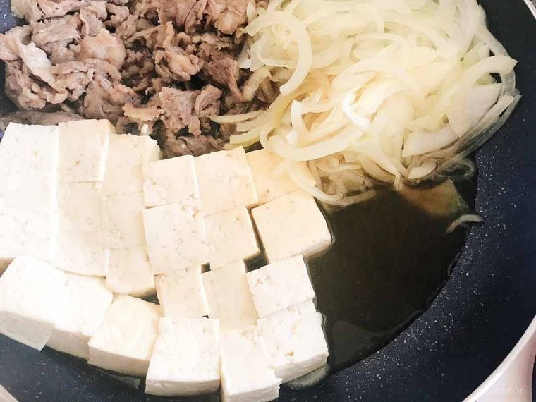 鍋の中にはいった牛肉、豆腐、玉ねぎを煮る