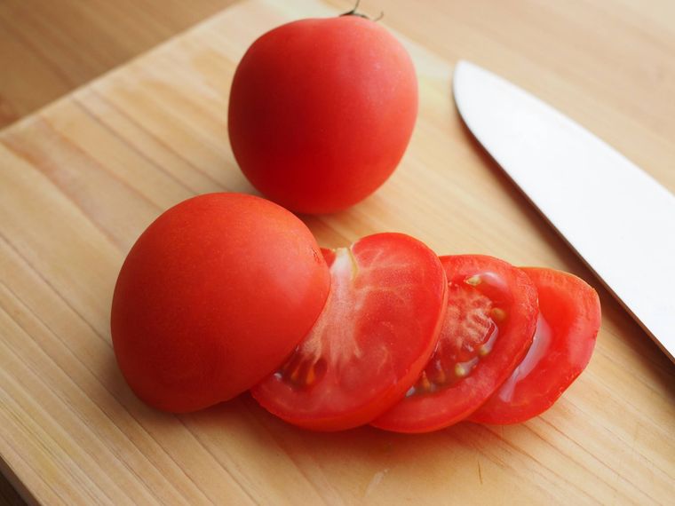 木のまな板でトマトを切っている様子